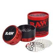 RAW brand modular steel pusher mill grinder shown with its red and black cylindrical container, open lid, inner chamber, and two silver metal milling plates